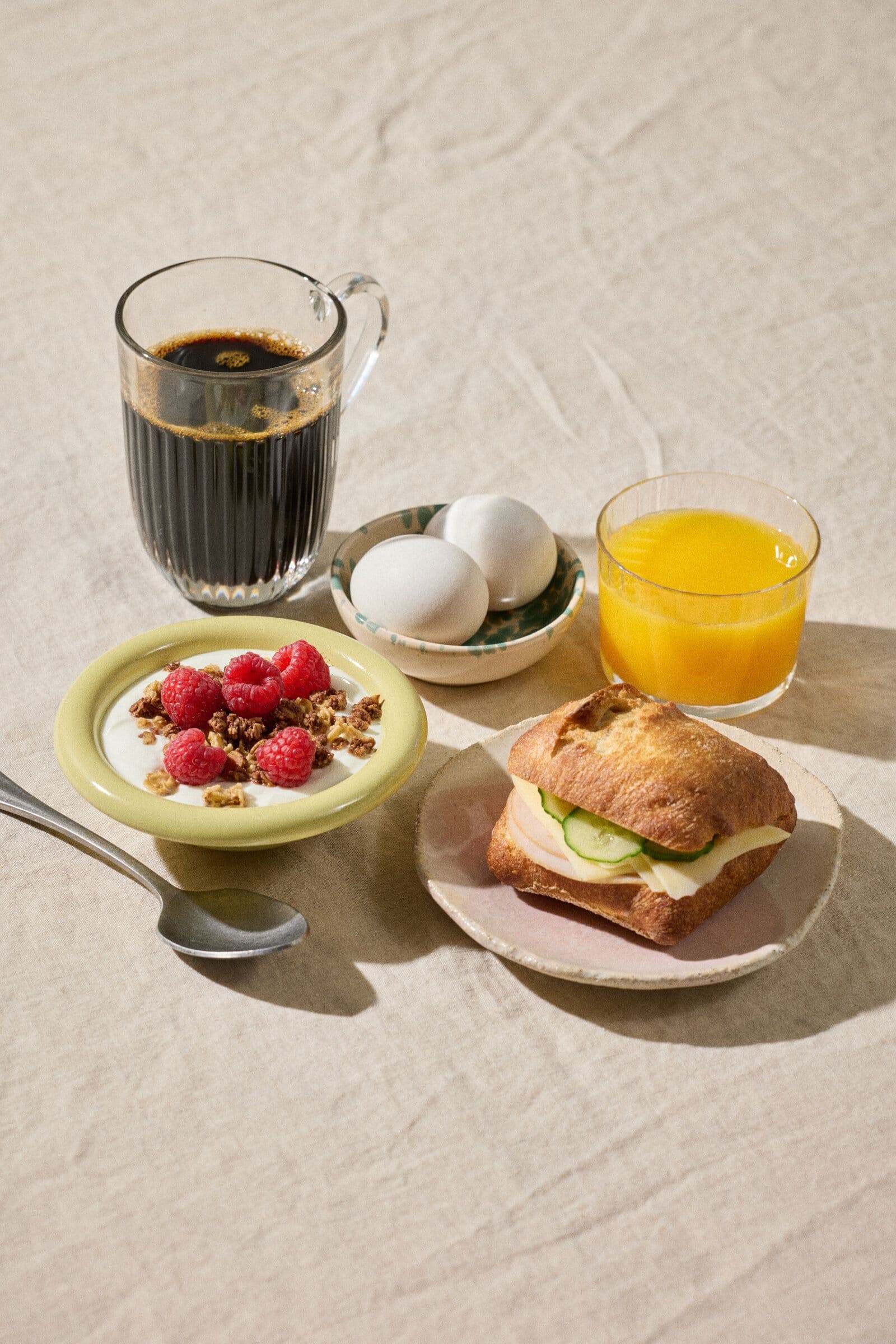 Morgenmad med græsk yoghurt, bær, æg, croissant og kaffe.
